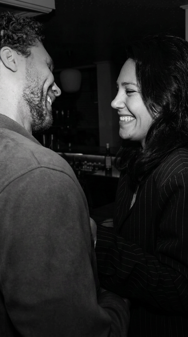 A smiling couple facing each other in a warmly lit bar